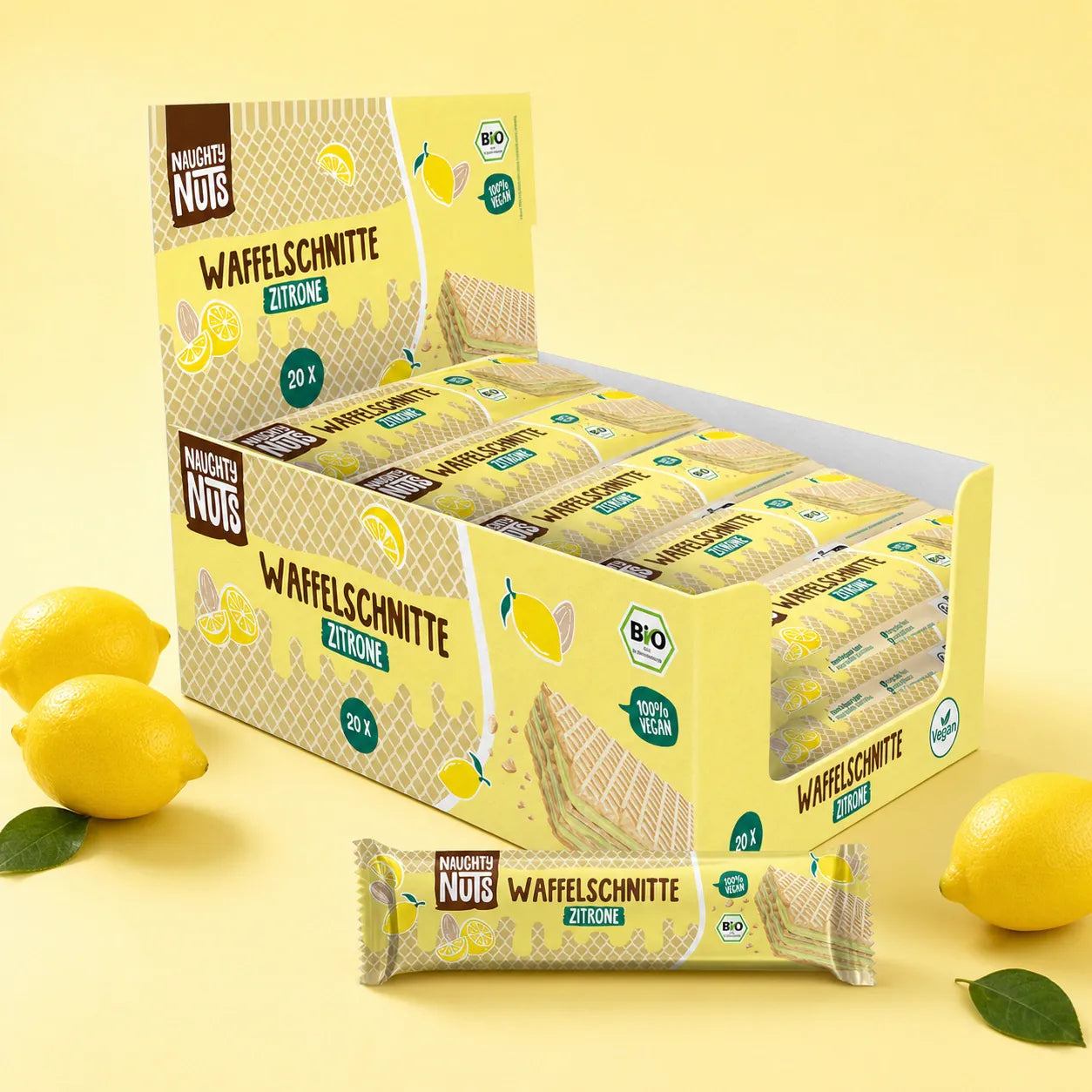 Verkaufsdisplay mit zwanzig Naughty Nuts Waffelschnitten Zitrone und frische Zitronen auf gelbem Hintergrund