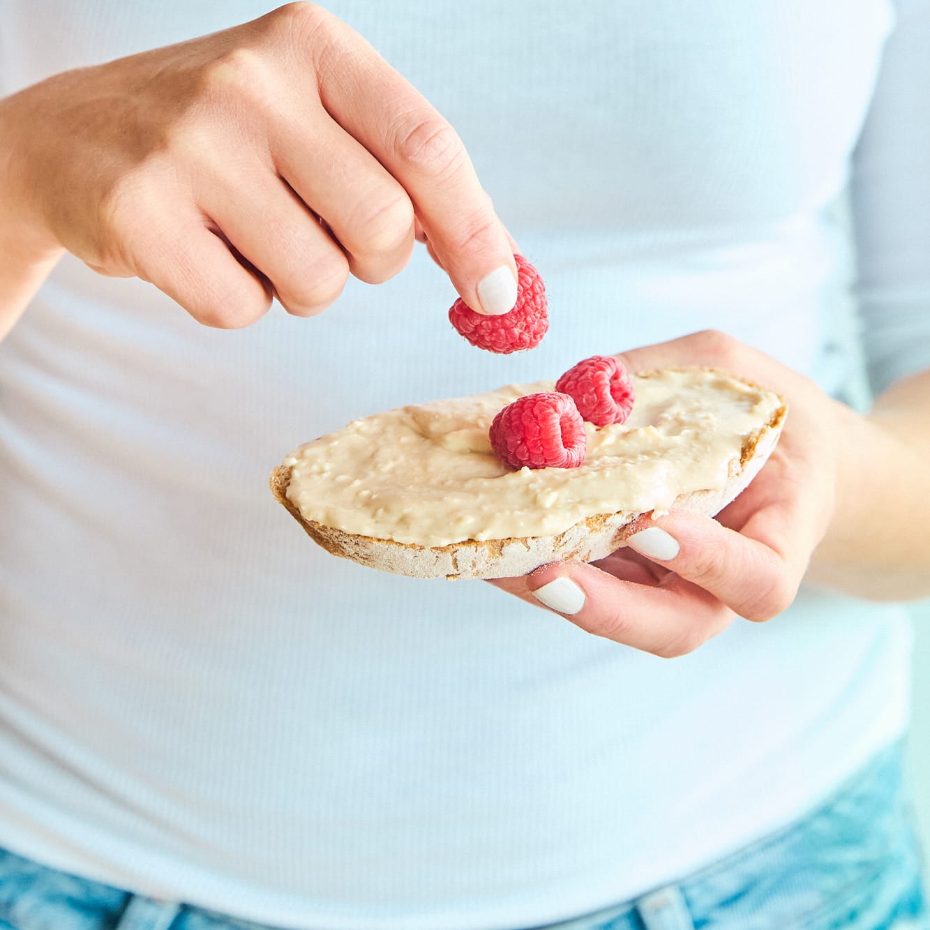 Frau belegt Brot mit Aufstrich Einsteiger Paket und Himbeeren